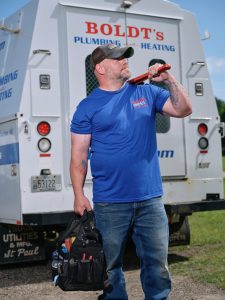 Technician inspecting an outdoor AC unit at a residential home in Hudson, WI